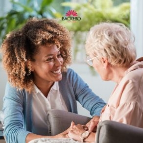 Leende personal pratar med äldre kvinna